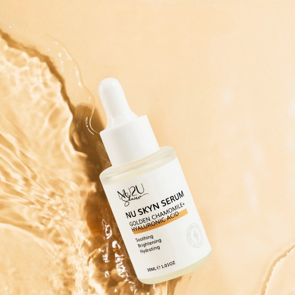 alt="NU Skyn Serum bottle rolling on clear water with peach background bottle reads NU Skyn Serum, Golden Chamomile + Hyaluronic Acid, soothing, brightening, hydrating."