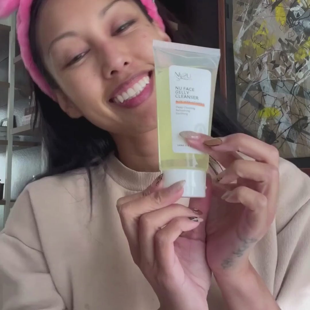 alt="Video of asian girl pouring NU Face Gelly Cleanser into her hand and applying to face, with pink bunny ears on head and wearing tan sweatshirt."